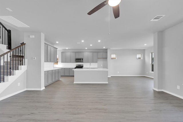 kitchen featuring visible vents, a sink, stainless steel appliances, gray cabinetry, and open floor plan