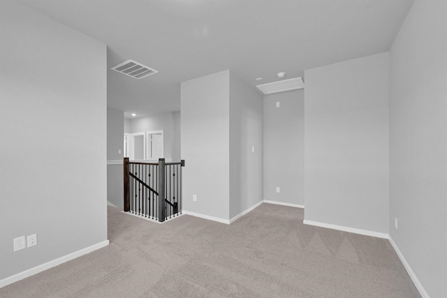 spare room featuring visible vents, carpet floors, baseboards, and attic access