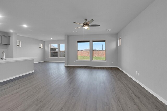 unfurnished living room featuring dark wood-type flooring, baseboards, and visible vents