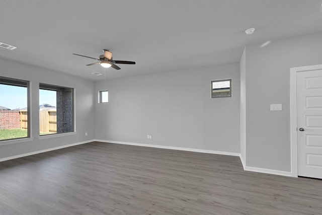 spare room with ceiling fan, visible vents, baseboards, and wood finished floors