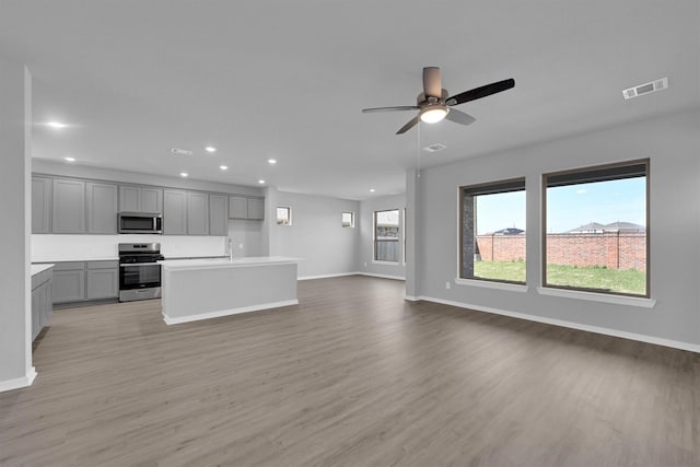 kitchen with open floor plan, light wood-style flooring, gray cabinets, and stainless steel appliances