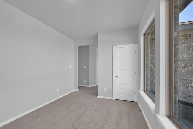 carpeted empty room with a wealth of natural light and baseboards