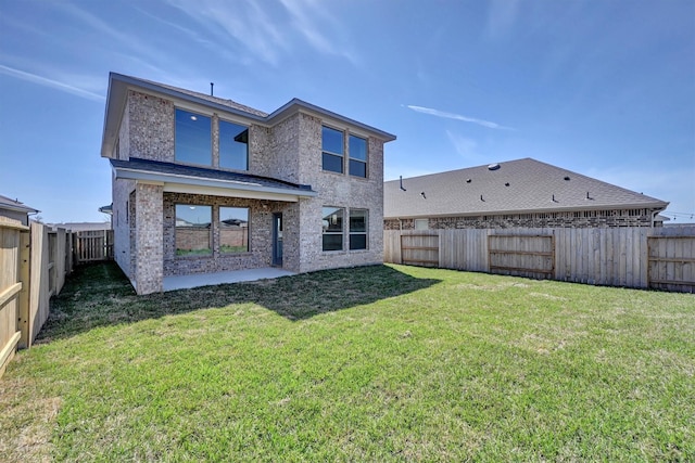 back of house with brick siding, a patio area, a lawn, and a fenced backyard