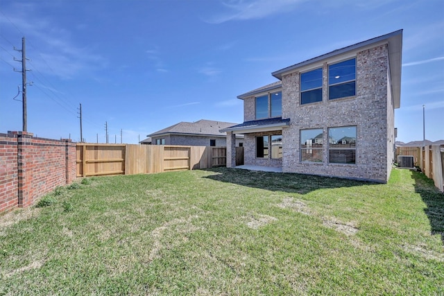 rear view of property with central air condition unit, a fenced backyard, a yard, brick siding, and a patio area