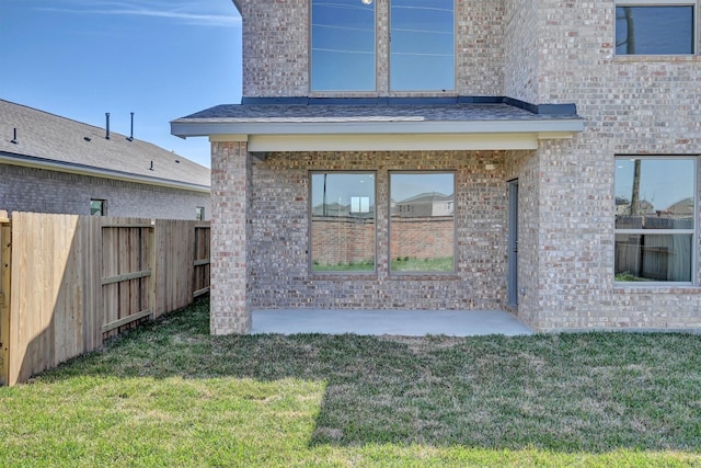 rear view of property with a yard, brick siding, and fence