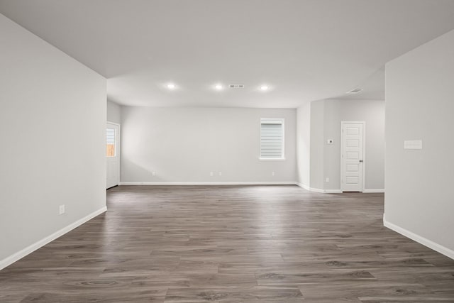 unfurnished room featuring dark wood-style floors, visible vents, and baseboards