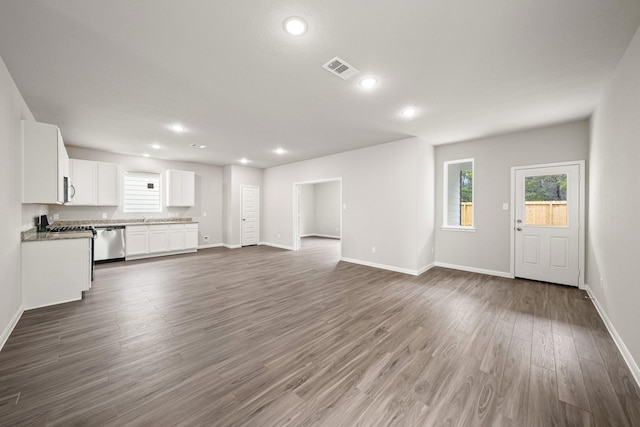 unfurnished living room with dark wood finished floors, visible vents, and baseboards