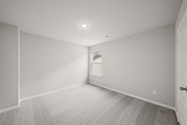 carpeted spare room featuring baseboards and visible vents