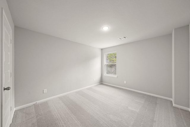 spare room featuring baseboards, visible vents, and light colored carpet