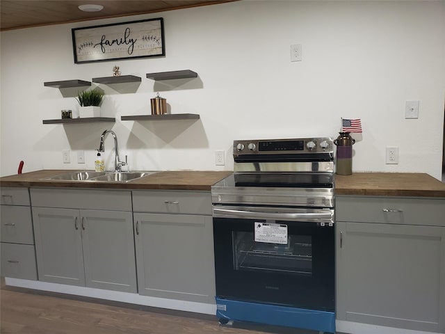 kitchen featuring gray cabinetry, wood counters, sink, and electric range