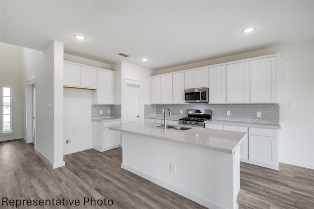 kitchen featuring stainless steel appliances, a center island with sink, and white cabinets