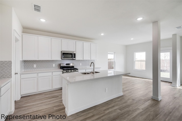 kitchen with a kitchen island with sink, sink, white cabinets, and appliances with stainless steel finishes