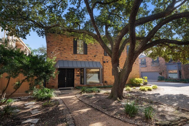 view of front of property featuring a garage, brick siding, metal roof, and a standing seam roof