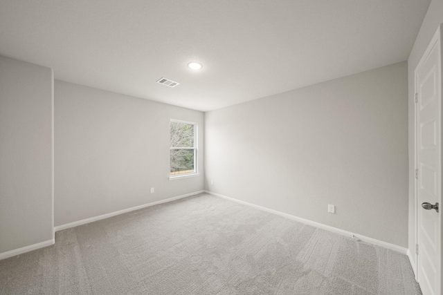 spare room featuring carpet floors, visible vents, and baseboards