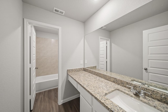 full bathroom featuring a washtub, wood finished floors, vanity, baseboards, and visible vents