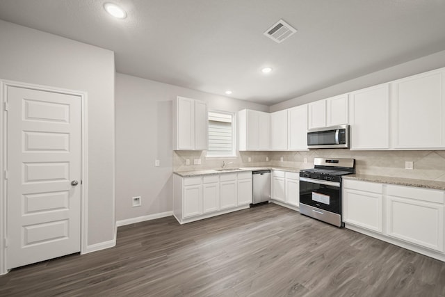 kitchen featuring light stone countertops, white cabinetry, appliances with stainless steel finishes, and a sink