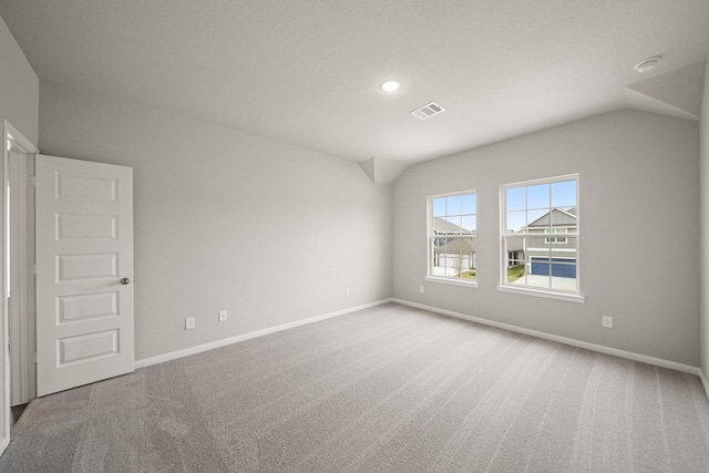 unfurnished room featuring carpet flooring, vaulted ceiling, visible vents, and baseboards