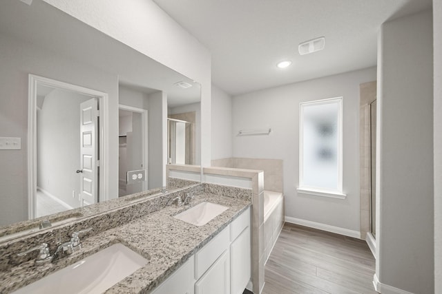 full bath featuring baseboards, a sink, a bath, and double vanity