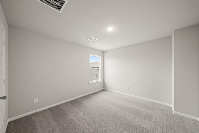 carpeted spare room featuring baseboards and visible vents