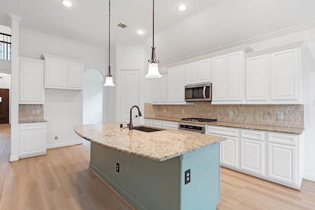 kitchen featuring sink, white cabinetry, stainless steel appliances, light stone countertops, and a kitchen island with sink