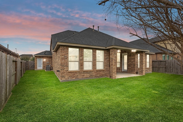 back house at dusk with a yard and a patio