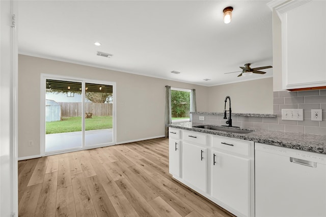 kitchen with stone countertops, sink, white cabinets, and white dishwasher