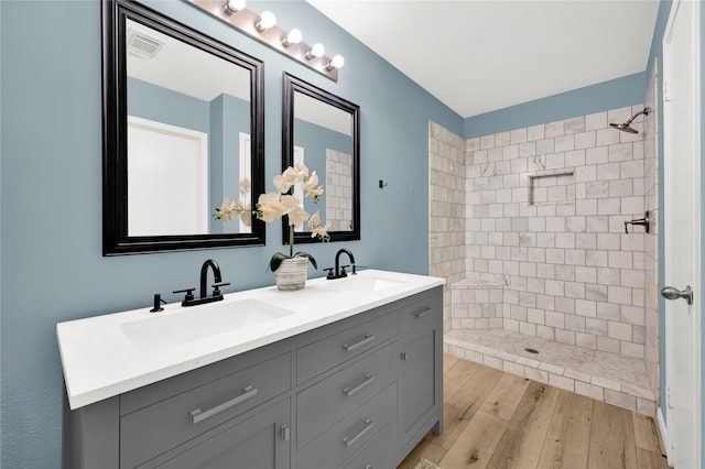 bathroom featuring hardwood / wood-style flooring, vanity, and a tile shower