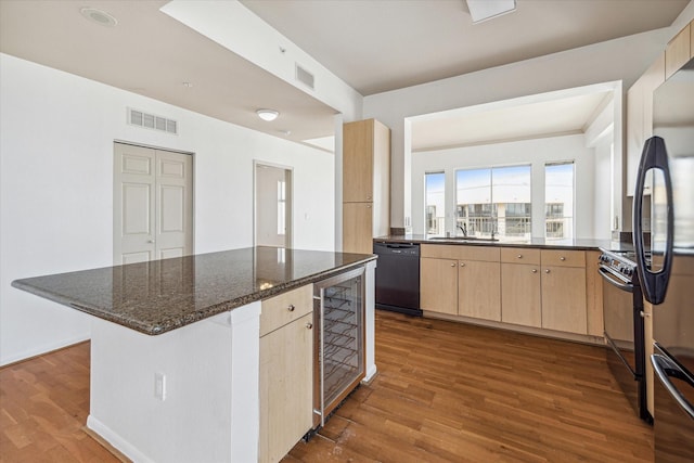 kitchen featuring black appliances, visible vents, dark stone countertops, and light brown cabinetry