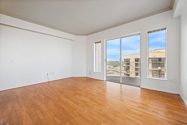 spare room with light wood-style flooring, baseboards, and crown molding