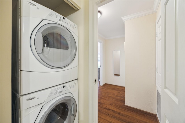 laundry area with crown molding, stacked washer and clothes dryer, and dark hardwood / wood-style floors