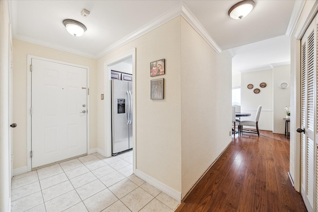 foyer with ornamental molding and light hardwood / wood-style floors