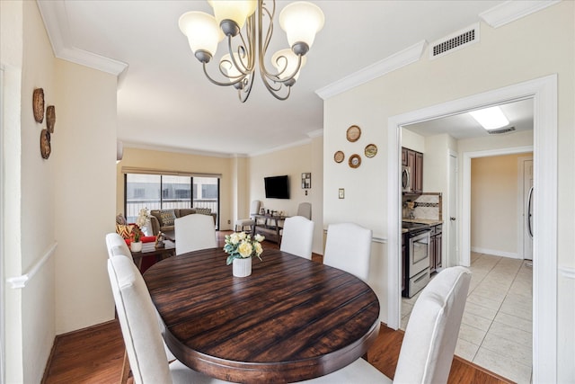 dining area featuring light hardwood / wood-style flooring, ornamental molding, and a chandelier