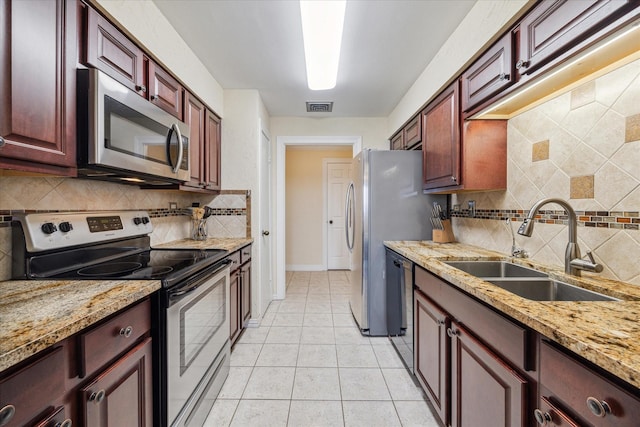 kitchen featuring light stone counters, sink, light tile patterned floors, and appliances with stainless steel finishes