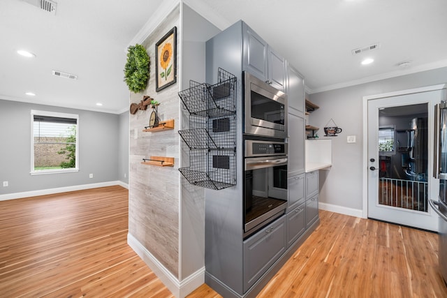 kitchen featuring ornamental molding, appliances with stainless steel finishes, light hardwood / wood-style flooring, and gray cabinetry