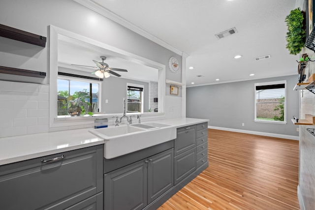 kitchen with gray cabinets, ornamental molding, and decorative backsplash