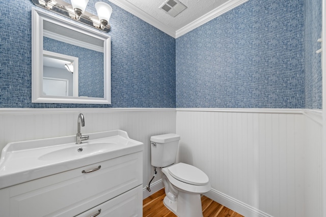 bathroom featuring toilet, crown molding, a textured ceiling, vanity, and hardwood / wood-style floors