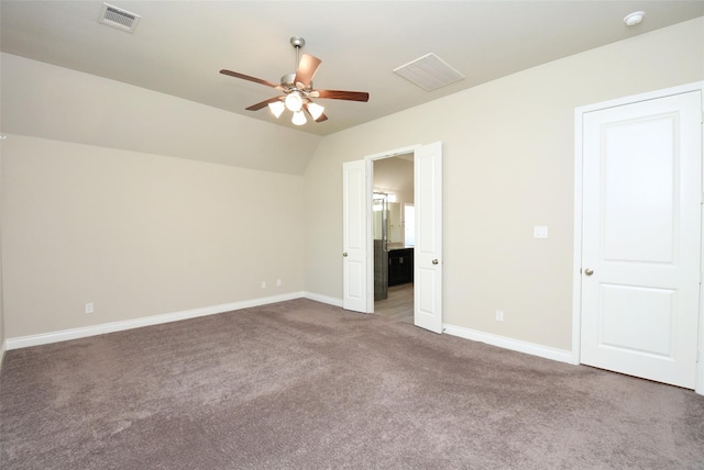 unfurnished bedroom featuring vaulted ceiling, carpet floors, connected bathroom, and ceiling fan