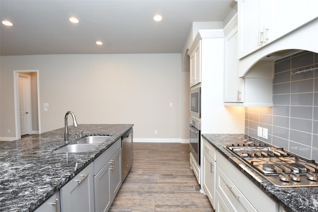 kitchen featuring sink, white cabinetry, appliances with stainless steel finishes, dark stone counters, and backsplash