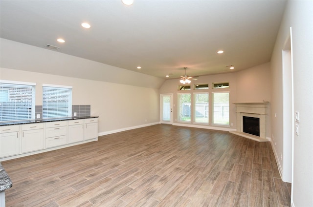 unfurnished living room with ceiling fan, lofted ceiling, and light wood-type flooring