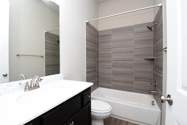 full bathroom with vanity, tiled shower / bath, hardwood / wood-style flooring, and toilet