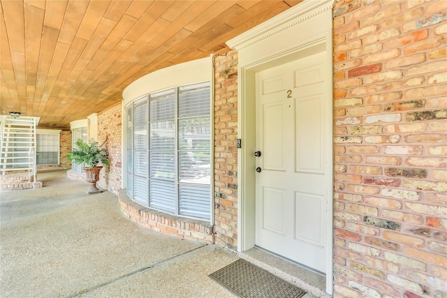 entrance to property with a porch and brick siding