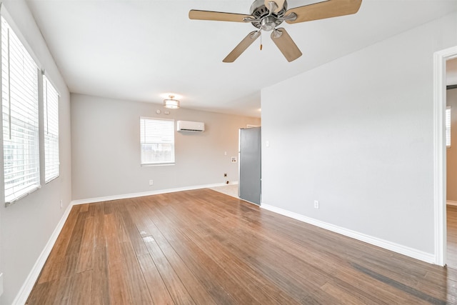 spare room with wood-type flooring, a wall mounted air conditioner, and ceiling fan