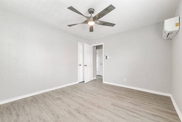 empty room with ceiling fan, a wall mounted AC, and light hardwood / wood-style floors