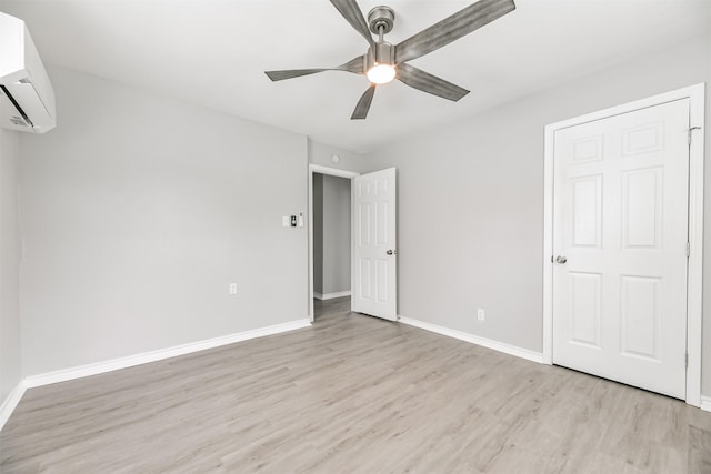 unfurnished bedroom featuring ceiling fan, a wall mounted AC, and light hardwood / wood-style floors