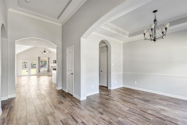 unfurnished room featuring ornamental molding, a tray ceiling, ceiling fan with notable chandelier, and light hardwood / wood-style flooring