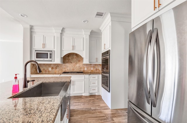 kitchen with appliances with stainless steel finishes, light stone countertops, and white cabinets