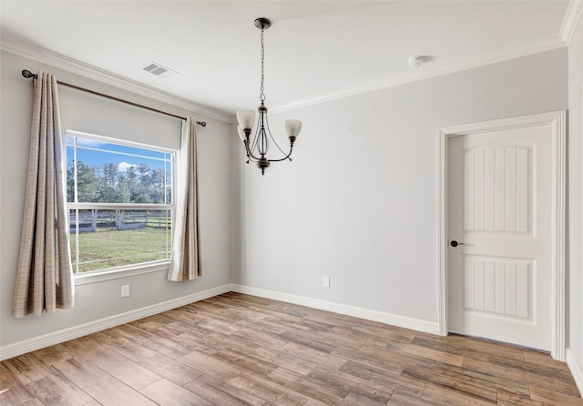 spare room featuring hardwood / wood-style flooring, crown molding, and a chandelier