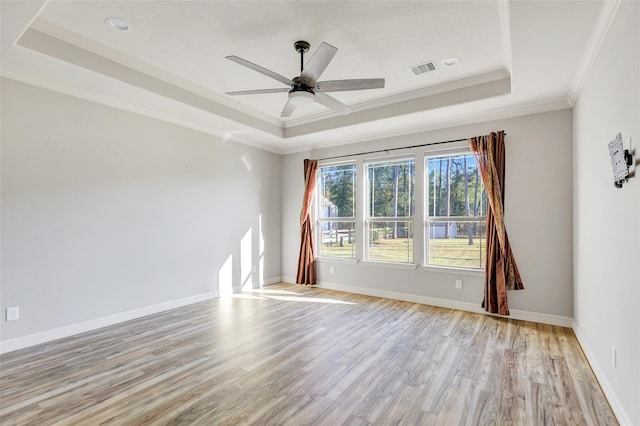 unfurnished room with ceiling fan, ornamental molding, a tray ceiling, and light hardwood / wood-style floors