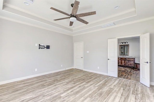 spare room featuring crown molding, ceiling fan, a raised ceiling, and light wood-type flooring