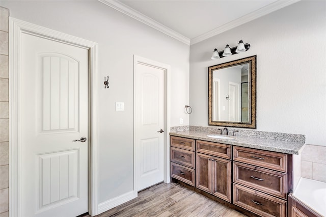 bathroom featuring ornamental molding, a bathing tub, wood-type flooring, and vanity